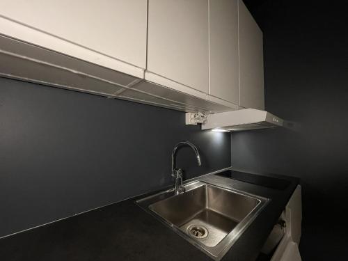 a kitchen with a stainless steel sink and white cabinets at The Hedge Apartments in Oslo