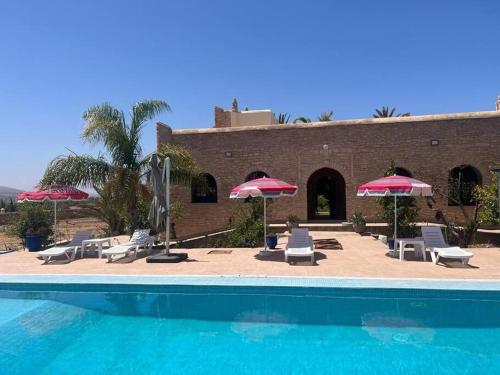une piscine avec des chaises et des parasols et un bâtiment dans l'établissement Villa Essaouira, à Essaouira