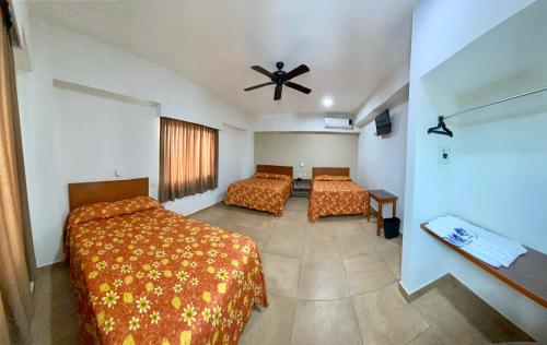 a bedroom with two beds and a ceiling fan at Hotel Delfines in Veracruz