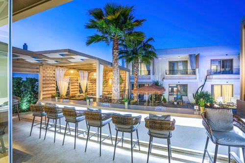 a patio with chairs and a bar with palm trees at Pefki Deluxe Residences in Pefkohori