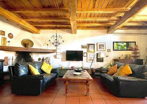 sala de estar con sofás de cuero negro y mesa de centro en Country Loft in antico monastero, Capena - Roma, en Capena