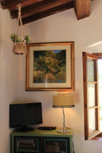 una televisione su un tavolo con una lampada e un quadro di AU-RA Vegan B&B a Castagneto Carducci