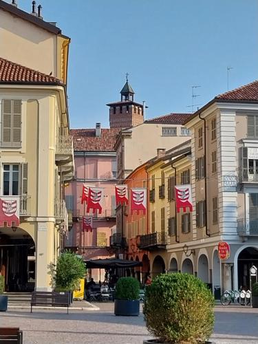 een groep gebouwen met vlaggen in een straat bij Casa Cozy - Comodo Appartamento in Asti Centro in Asti