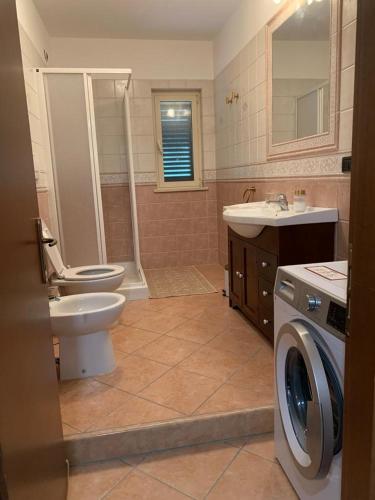 a bathroom with a toilet sink and a washing machine at Casa vacanze 365 - verde in Tortoreto Lido