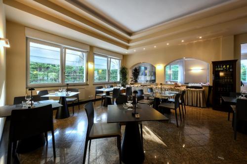 ein Restaurant mit Tischen, Stühlen und Fenstern in der Unterkunft Hotel Internazionale in Domodossola