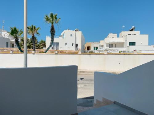 een witte muur met palmbomen en gebouwen bij La Casa sulla Spiaggia Torre San Giovanni in Torre San Giovanni Ugento