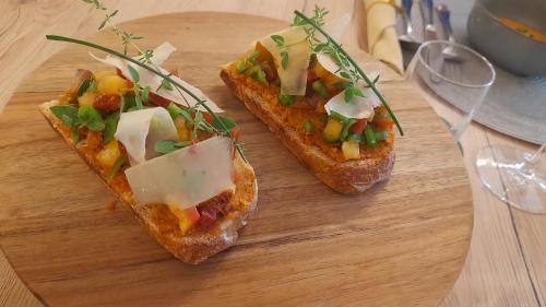 two pieces of toast with vegetables and cheese on a cutting board at La Parenthèse, chambres d'hôtes in Rochegude-Drome