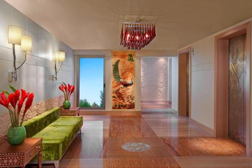 a living room with a green couch and a chandelier at ITC Gardenia, a Luxury Collection Hotel, Bengaluru in Bengaluru