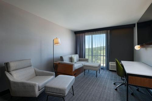 a living room with a couch and a chair and a desk at Courtyard by Marriott Austin Dripping Springs in Dripping Springs