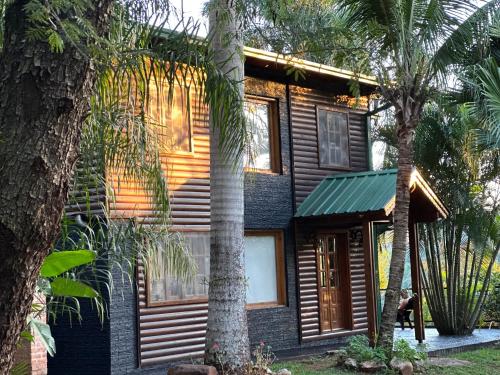 a wooden house with palm trees in front of it at Costa del Sol Iguazú in Puerto Iguazú