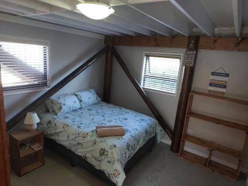 a small bedroom with a bed and two windows at Penelope Selfcatering Apartment in Wilderness