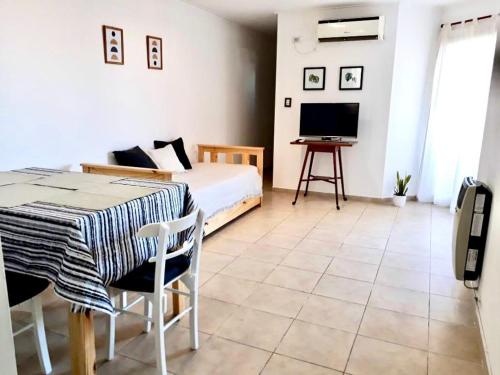 een slaapkamer met een bed, een tafel en een televisie bij Departamento Vista Bella, céntrico y cercano a la terminal, Exc ubicación, playa estacionamiento cercana-económica in Villa María