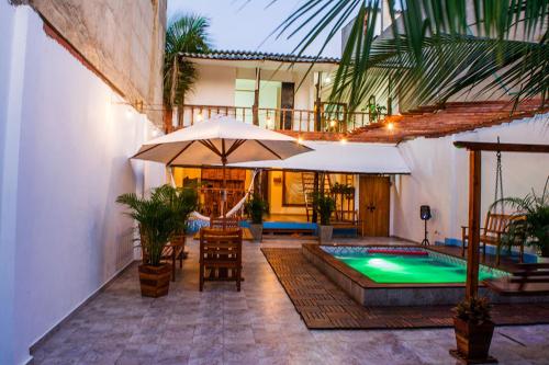 un patio con piscina, sombrilla y sillas en HOSTAL LA BOQUILLA en Cartagena de Indias