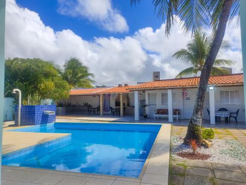 una piscina davanti a una casa con palme di Vivenda das Águas Guarajuba a Guarajuba