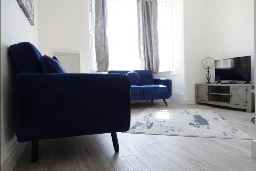 a living room with a blue couch and a tv at West Lake District Comfort Stays in Maryport town centre in Maryport