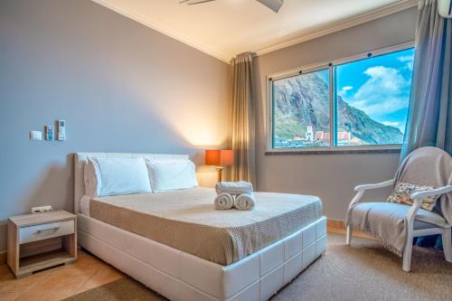 ein Schlafzimmer mit einem Bett, einem Stuhl und einem Fenster in der Unterkunft Front beach Apartment in Paul do mar 9 in Paul do Mar