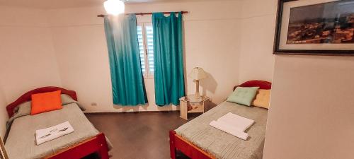 two beds in a room with green curtains at DUPLEX a metros de NVA CBA con TERRAZA ASADOR y OPCIONAL COCHERA in Cordoba