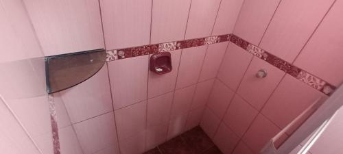 ein Badezimmer mit einer rosa gefliesten Dusche und einem Seifenspender in der Unterkunft TahuanWasi Apartments in Cusco