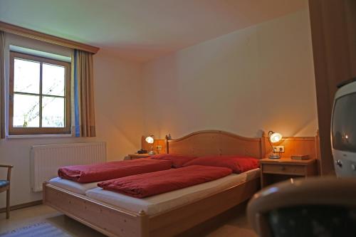 a bedroom with a bed with red sheets and a window at Appartementhaus Wehrenfennig in Gosau