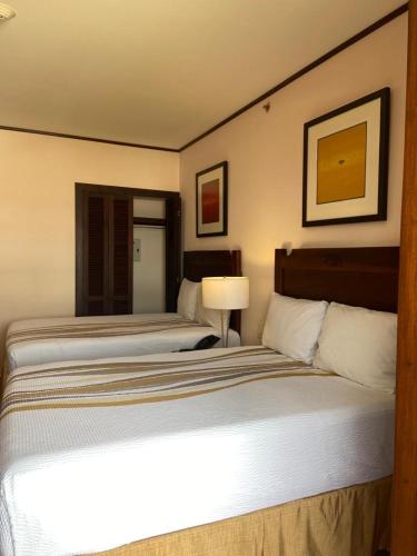 a hotel room with two beds and a lamp at Hotel La Recolección in León