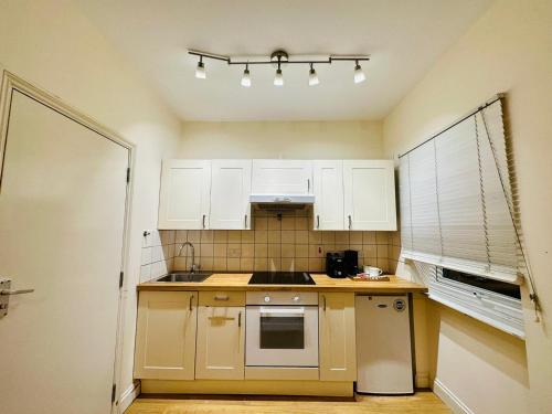 a kitchen with white cabinets and a stove top oven at Premium Studio Flat 02 Near Tower Bridge in London