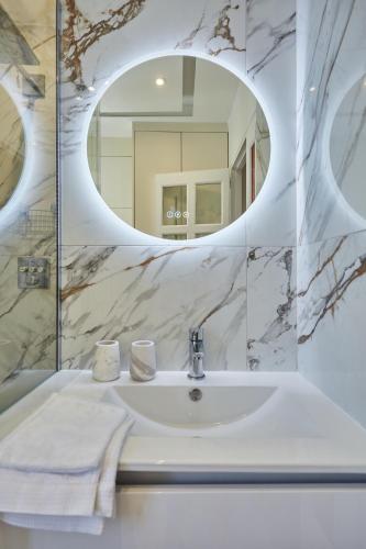 une salle de bain avec un lavabo et un miroir dans l'établissement SaintGermainByCecile - Luxueux 2 pièces AC Bianca, à Paris