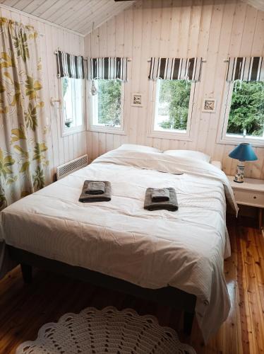 a bedroom with a large bed with white sheets and windows at Ljungdahl in Korppoo