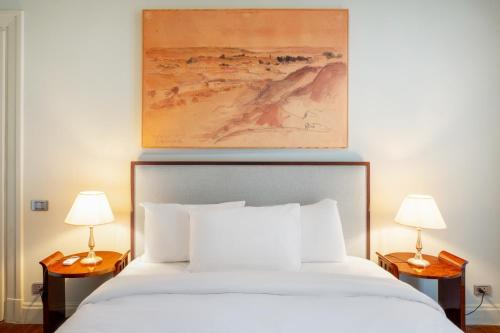 a bedroom with a white bed with two lamps at Brassbell l DT l Art Deco Designer Apartments in Cairo