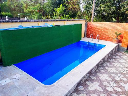 埃爾博斯克的住宿－La Casa del Naturalista，蓝色的游泳池四周环绕着绿色的围栏