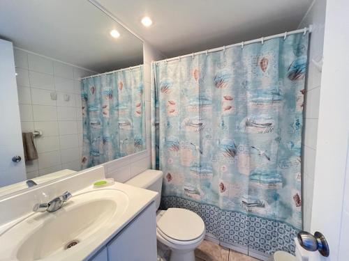 Un baño con lavabo, inodoro y cortina de ducha. en Euromarina 1,Espectacular vista ! Playa Cochoa, en Viña del Mar