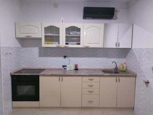 uma cozinha com armários brancos e um lavatório em Apartman Milenkovic em Malo Laole