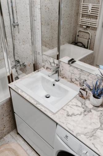 a white bathroom with a sink and a mirror at Jak u siebie w domu. Apartament w nowej dzielnicy. in Tczew