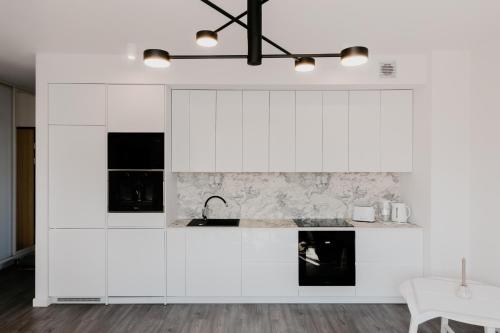 a kitchen with white cabinets and a sink at Jak u siebie w domu. Apartament w nowej dzielnicy. in Tczew