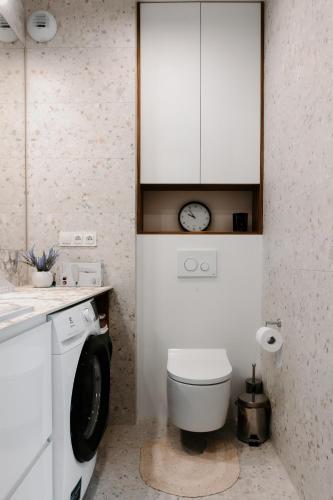 a bathroom with a toilet and a clock on the wall at Jak u siebie w domu. Apartament w nowej dzielnicy. in Tczew