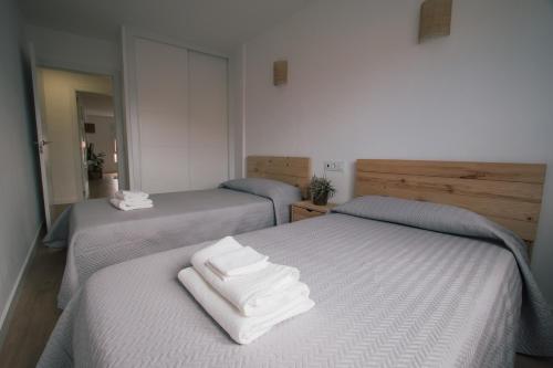 2 camas con toallas blancas en una habitación en Laxiela Apartment en O Grove