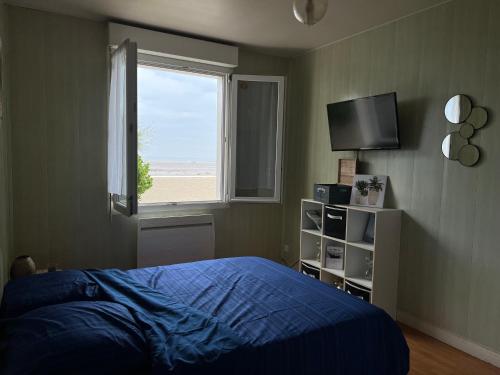 a bedroom with a bed and a window and a television at Maison les pieds dans l'eau in Quinéville