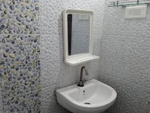 ein Bad mit einem Waschbecken und einem Spiegel in der Unterkunft Goroomgo Kanha Inn Lucknow in Lucknow