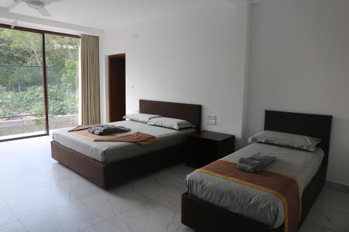 a bedroom with two beds and a large window at Amanda Beach Resort in Pasikuda