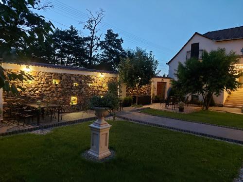 a yard with a stone wall and a vase in the grass at Conacul Poetilor in Gura Rîului