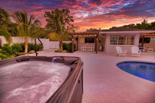um quintal com uma banheira de hidromassagem e uma casa em Tropical Oasis, Heated Pool, Hot Tub, Near Siesta Key em Sarasota