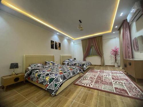 a bedroom with two beds and a rug at فيلا للايجار اليومى اوالشهرى فى الريف الاوربي- طريق مصر اسكندرية الصحراوى- قريبة من مطار سفنكس -بجوار هايبر وان الصحراوى in Qaryat ash Shamālī