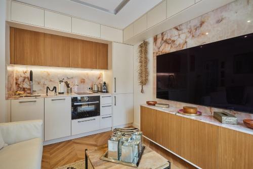 Il comprend une cuisine avec des placards blancs et une grande télévision à écran plat. dans l'établissement SaintGermainByCecile - Luxueux 2 pièces AC Bianca, à Paris
