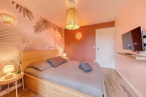 Schlafzimmer mit einem Bett und einem TV an der Wand in der Unterkunft Disney Jungle Cottage - Near Disneyland in Thorigny-sur-Marne