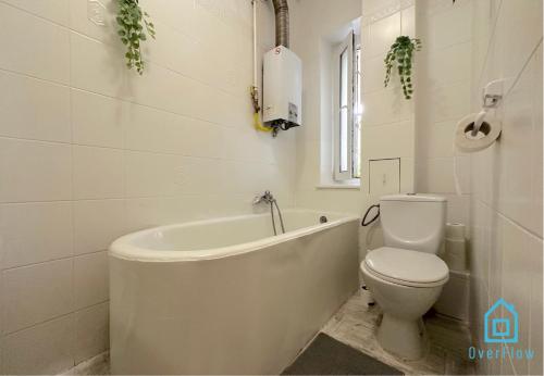a white bathroom with a tub and a toilet at Ocular Room in Gdańsk