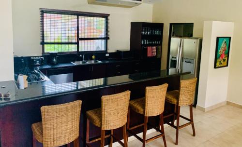 a kitchen with a bar with chairs and a refrigerator at Sublime Villa in the Heart of Playa Coronado in Playa Coronado