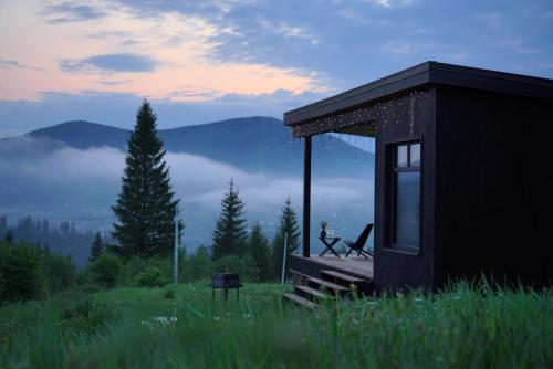 a cabin in a field with a view of the mountains at Chilloutzonе - Будинок з безкоштовним джакузі та кінотеатром in Slavske