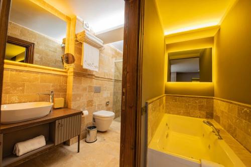 a yellow bathroom with a tub and a sink at Four Mansions Hotel in Kayseri