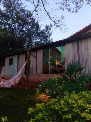 a house with a hammock in front of it at Pousada Canto Feliz in Serra do Cipo