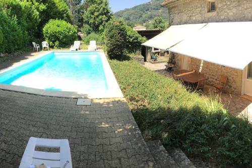 une piscine avec deux chaises et un parasol dans l'établissement GRANDE MAISON FAMILIALE EN PIERRES SUD ARDÈCHE, à Lalevade-dʼArdèche