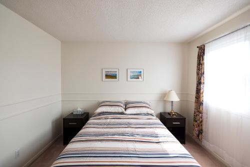 a bedroom with a bed with two night stands and a window at The Comfort Stay at City of Pickering in Pickering